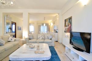 ein Wohnzimmer mit einem Sofa und einem TV in der Unterkunft Melitta Villa in Ágios Ioánnis