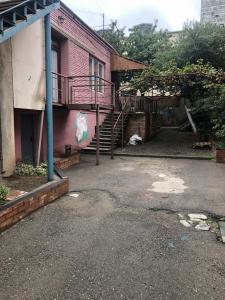 a pink building with a staircase next to a building at For Daily Rent in Tbilisi City