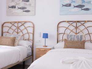 2 letti in una camera da letto con lenzuola e cuscini bianchi di Matarolux24 a Mataró