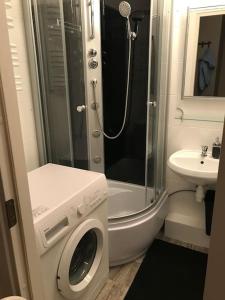 a bathroom with a shower and a washing machine at Przytulny apartament z bezpłatnym parkingiem in Olsztyn