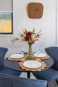 a table with two plates and a vase with flowers at Central City Escape 1 Bed 1 Bath near Hagley Park in Christchurch