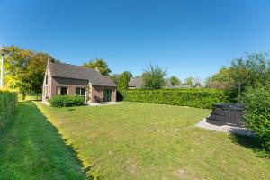 un patio con una casa y un cubo de basura en 6P Vrijstaand Huis met royale tuin en Hottub, en Ewijk