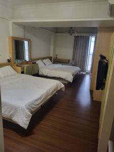 a hotel room with two beds and a television at 美達民宿 in Donggang