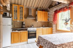 eine Küche mit Holzschränken und einem weißen Kühlschrank in der Unterkunft Cottage with Hot tub and Sauna in Uurainen