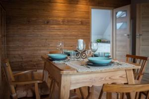 a wooden table with bowls and wine glasses on it at Zubrzyckie Pokoje in Zubrzyca Dolna