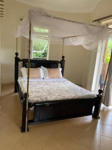 a bedroom with a canopy bed with a window at Rafiki Safari Lodge Bwindi in Kinkizi
