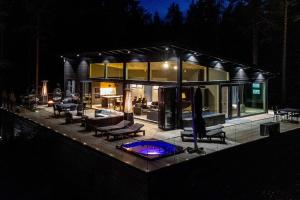 Villa Padel - Premium Lakeside Residence & Grounds في Lohja: منزل زجاجي كبير مع حمام سباحة في الليل