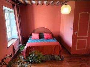 Cette chambre rouge comprend un lit avec deux oreillers roses. dans l'établissement Gîte Design, à Arceau