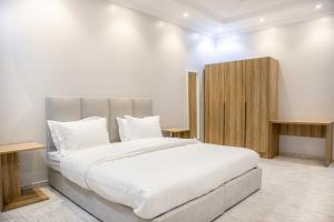AR Rummanah的住宿－Luxurious Family Apartments 15Mins Drive to Al-Masjid Nabawi - Qaswarah residence，卧室配有一张白色大床和木制橱柜。
