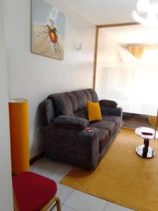ein Wohnzimmer mit einem braunen Sofa und einem roten Stuhl in der Unterkunft Tsavo 90 degrees smart view in Nairobi