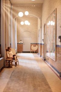 アムステルダムにあるPillows Grand Boutique Hotel Maurits at the Park - Small Luxury Hotelsの廊下の椅子に座る女性