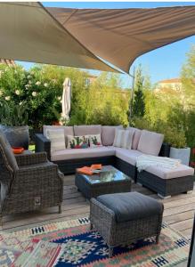 un patio con sofá, sillas y sombrilla en La Batie Saint-André en Redessan