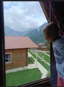 a child looking out of a window at a house at Thethi Paradise in Theth