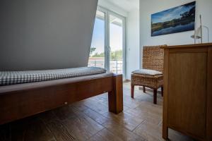 - une chambre avec un lit, une chaise et une fenêtre dans l'établissement DER STÖRTEBEKER - "Apartment Ahrenshoop" Apartments hinter den Dünen, à Dierhagen