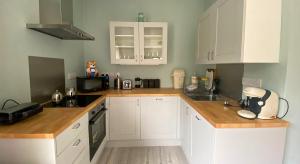 Donegal Town House في دونيجال: مطبخ مع خزائن بيضاء وقمم منضدة خشبية