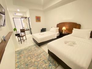 a hotel room with two beds and a table and chairs at The Courtyard Chiangrai in Chiang Rai +149 photos