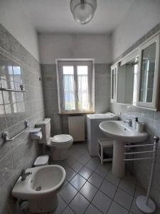 Baño blanco con 2 lavabos, aseo y lavamanos en La casa dei nonni, en Lucca