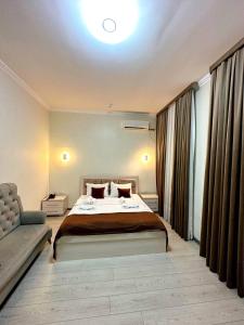 IZZA PALACE Hotel في طشقند: غرفة نوم بسرير كبير وأريكة