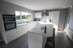 a kitchen with white cabinets and a counter with two wine glasses at Millbay View House in Kilkeel
