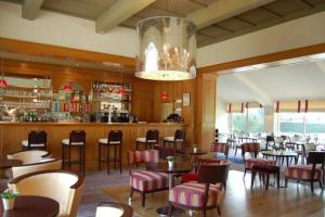 un restaurant avec des tables et des chaises ainsi qu'un bar dans l'établissement Cottage spacieux Domaine de la Bretesche, à Missillac