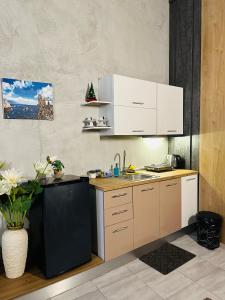 a kitchen with white cabinets and a black refrigerator at Colombia Apartments&Rooms in Durrës