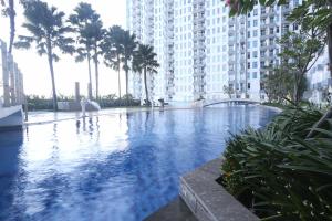 a large swimming pool with palm trees and buildings at Pinky Rose @Anderson Apartment in Surabaya