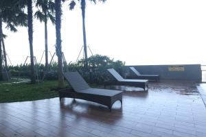 a patio with two lounge chairs and palm trees at Pinky Rose @Anderson Apartment in Surabaya