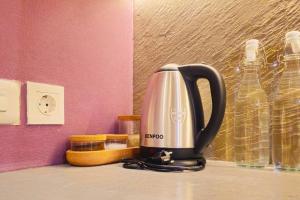 a tea kettle sitting on a counter next to glass bottles at Pinky Rose @Anderson Apartment in Surabaya