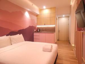 a bedroom with a white bed and a kitchen at Pinky Rose @Anderson Apartment in Surabaya +10 photos