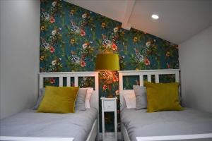 two beds in a bedroom with a floral wallpaper at Llansteffan 2-Bed Cottage Sleeps 4 Dog Ok in Carmarthen