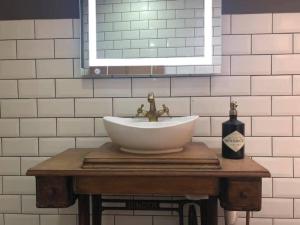 un lavabo en una mesa de madera con una botella de vino en Luxury 2-Bed Cottage in Llansteffan, en Carmarthen
