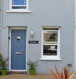 a blue door on a white house with a window at Luxury 2-Bed Cottage in Llansteffan in Carmarthen