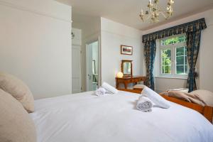 a bedroom with a bed with white sheets and a window at Cliff Cottage in Brixham