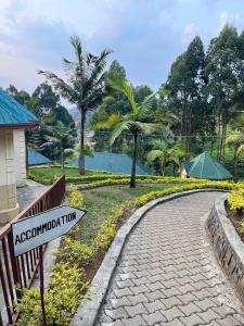 a street sign in front of a park with palm trees at EAR KEN BARHAM GUESTHOUSE in Rwumba