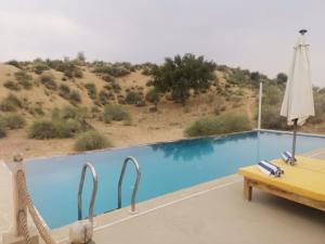 a table and chairs next to a swimming pool at Dhora Desert Resort, Signature collection by Eight Continents in Shaitrāwa