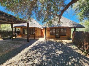 a brick house with a tree in front of it at Bateleur Lodge, Mabalingwe in Warmbaths
