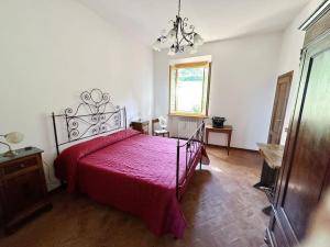 a bedroom with a bed with a red bedspread at Casale di Valle Mora in San Gimignano