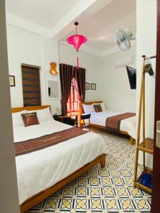 um quarto de hotel com duas camas e um candeeiro rosa em SEVEN HOMESTAY(HUE) em Hue