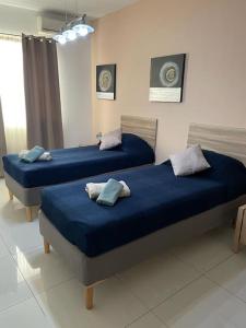 2 camas en una habitación con sábanas y almohadas azules en Mensija, en San Julián