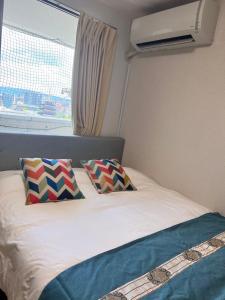 een bed met 2 kussens in een kamer met een raam bij 大阪旅・四葉　 in Osaka