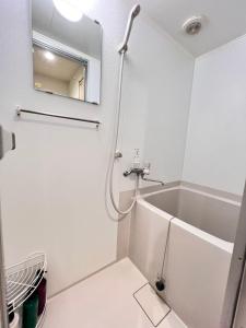 a white bathroom with a tub and a mirror at 大阪旅・四葉　 in Osaka