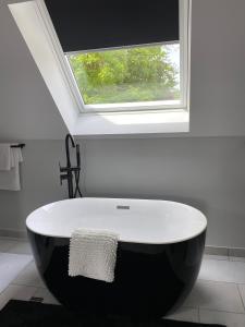 uma banheira em preto e branco numa casa de banho com uma janela em Le Baptistère - Adults only em Attichy