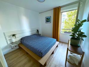 een slaapkamer met een bed en een raam met een plant bij uta house la plaine in Saint-Denis