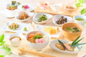 een tafel met kommen eten en eetstokjes bij Ooedo Onsen Monogatari Nagayama in Kaga