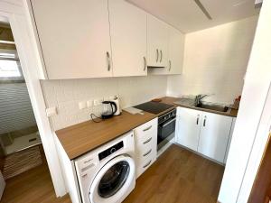 een keuken met witte kasten en een wasmachine bij Sea View Apt - 2 min walk to the Beach & 200 Mbit Highspeed internet in Larnaka
