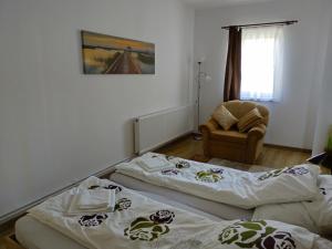 two beds in a room with a chair at TSG apartament 2 in Valea lui Mihai