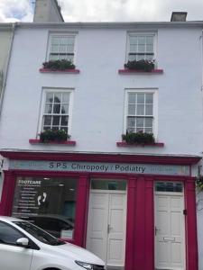 a white building with red doors and windows at Perfect Apartment in ideal location in Ennistymon