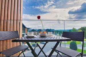 une table avec une fleur dans un vase sur un balcon dans l'établissement Apartamenty Laguna Beskidów - A95, à Zarzecze