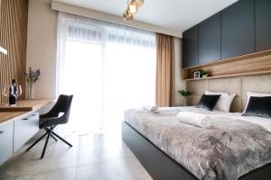 - une chambre avec un grand lit, un bureau et une chaise dans l'établissement Apartamenty Laguna Beskidów - A95, à Zarzecze