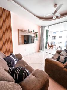 sala de estar con 2 sofás y TV de pantalla plana en Apt na Praia do Morro,2 quadras do mar,com Garagem, en Guarapari